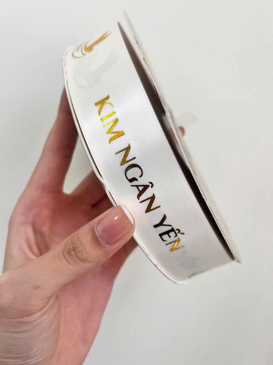 Kim vàng nổi bật trên nền ruy băng trắng.